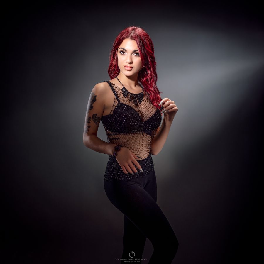 ragazza lingerie nera in piedi sfondo neutro luce drammatica moody e sexy