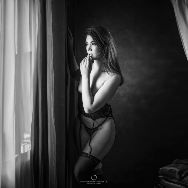 donna in lingerie nera in camera da letto che guarda fuori finestra con atteggiamneto sexy e glamour boudoir