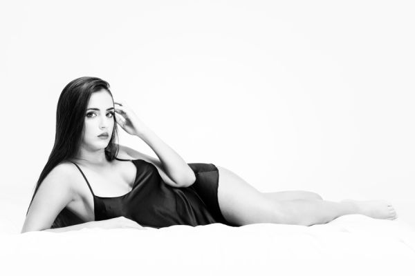 ragazza in intimo nero di seta sdraiata letto in bianco e nero BW in luce alta